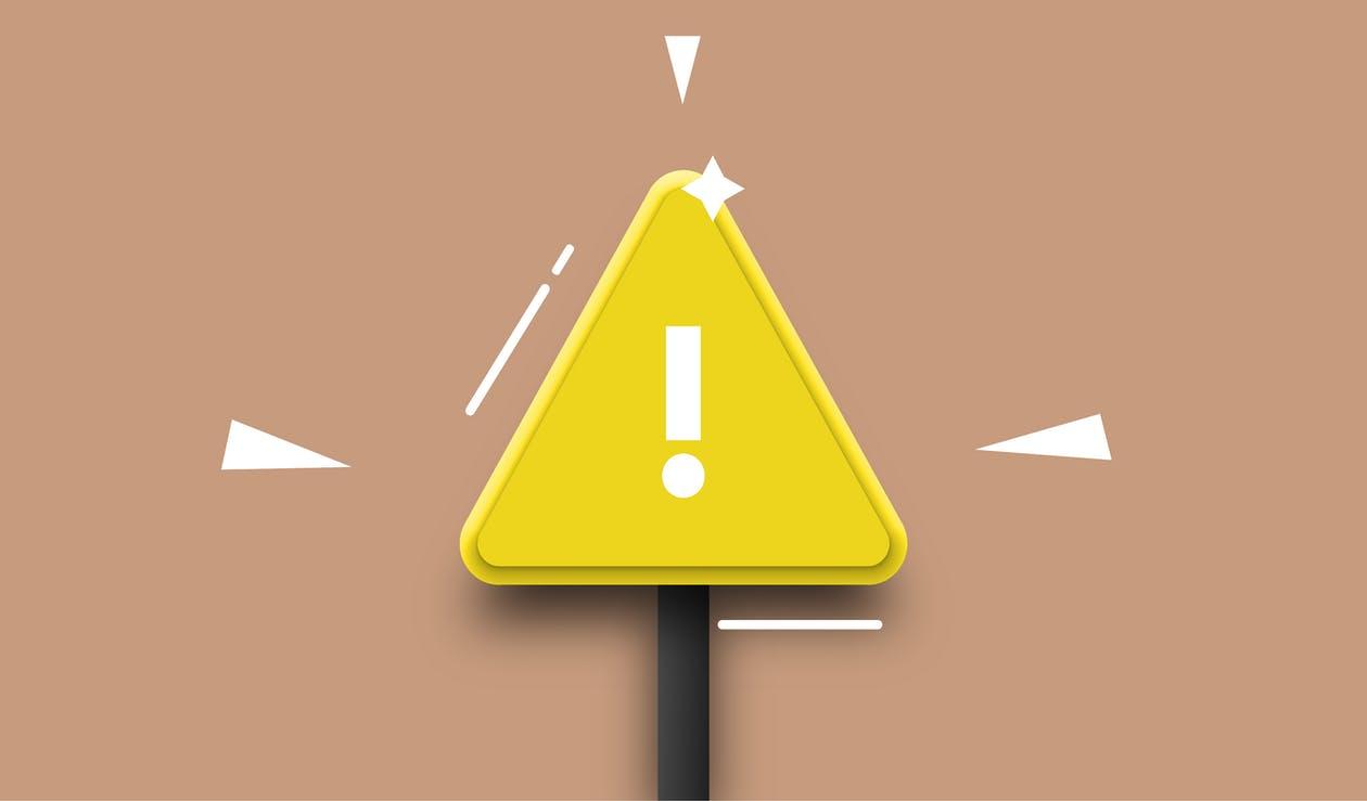 Imagem com fundo creme escuro e com sinal de alerta amarelo